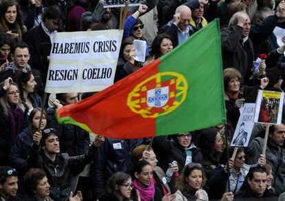 Un manifestante sostiene una pancarta exigiendo la renuncia del Primer Ministro de Portugal junto a una bandera portuguesa, en una manifestaci&oacute;n contra las medidas de austeridad aplicadas por el gobierno de Portugal.
