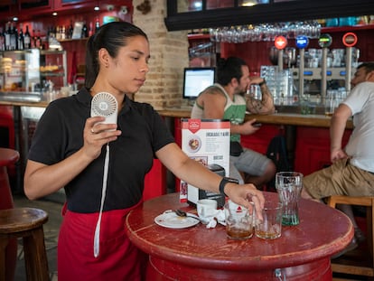 Una camarera se refresca con un pequeño ventilador de mano mientras trabaja en la Taberna El Papelón en Madrid.