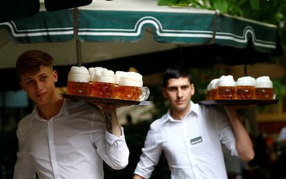 Camareros sirven cervezas en el local tradicional 'Schweizerhaus', en Viena (Austria).