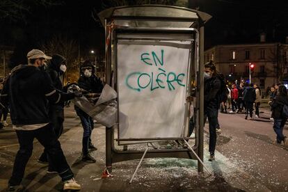 Un grupo de manifestantes retira la publicidad de una parada de autobús dañada que dice "enojado", durante una protesta en Dijon, el lunes.