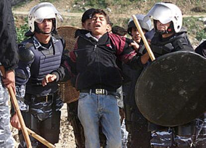 Policías antidisturbios palestinos arrestan a un joven simpatizante de Hamás que protestaba en Gaza por el arresto del líder radical Ahmed Yasín.