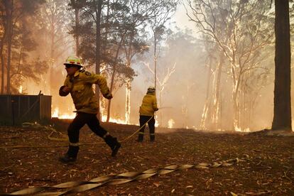 Oficiales de bomberos y de rescate de NSW protegen una casa en Wheelbarrow Ridge Road que se ve afectada por el incendio de Gospers Mountain al suroeste de Sydney (Australia).