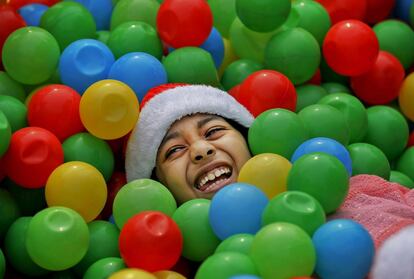 Retrato de una niña que juega entre bolas de colores en una fiesta de Navidad en Daca, Bangladesh.