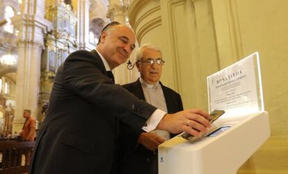 Juan Ignacio Zafra (CaixaBank), enseña al déan de la catedral de Málaga, Antonio Aguilera, cómo usar uno de los nuevos “cepillos digitales”.