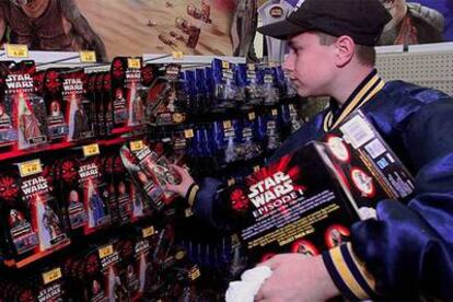 Un joven coloca juguetes de la saga 'Star Wars' en una tienda estadounidense.
