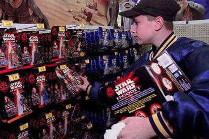 Un joven coloca juguetes de la saga &#39;Star Wars&#39; en una tienda estadounidense.