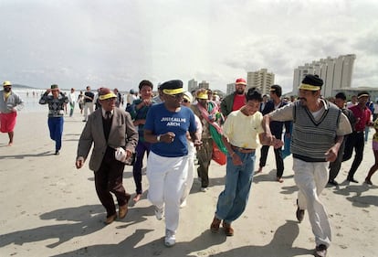 El arzobispo Desmond Tutu, en el centro, corre por una playa solo para blancos cerca de Ciudad del Cabo el 30 de septiembre de 1989 con una multitud de simpatizantes, dentro de la campaña de la Iglesia de desafío contra las leyes del ‘apartheid’.