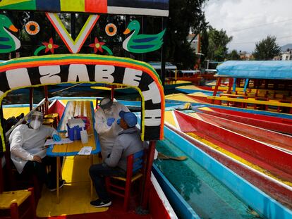 Médicos examinan a un hombre para detectar COVID-19 a bordo de una "trajinera" en  la alcaldía Xochimilco en la Ciudad de México, México.