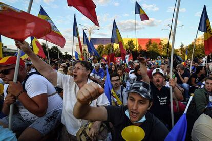 Varios manifestantes protestan este sábado en Bucarest contra el Gobierno con banderas rumanas.