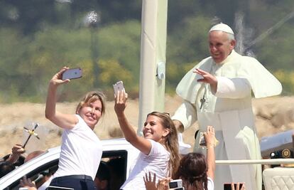 Dos asistentes a la misa multitudinaria del Papa tratan de hacerse una foto con él a su paso.