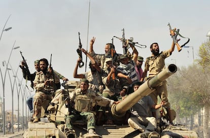 Rebeldes libios, subidos un tanque, hacen señales de victoria en su avance por las calles de Sirte.