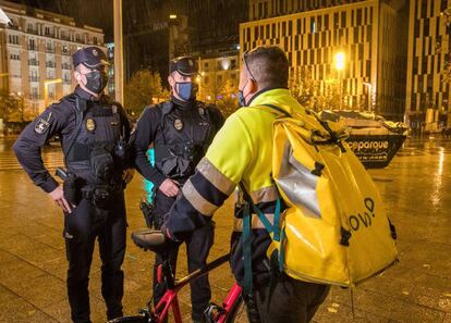 Unos policías informan a un repartidor sobre la aplicación del toque de queda en Zaragoza. El Gobierno de Aragón aplicará el toque de queda entre las 23.00 y las 06.00 horas y analizará si modifica esta franja horaria aprobada por el Ejecutivo central.