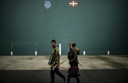 Dos personas caminan delante de una pared con la bandera vasca, en Hernani.