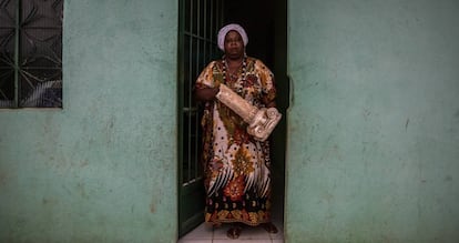 Mãe Vivian na porta da casa em Sepetiba com parte da estrutura da casa de Seropédica em mãos.