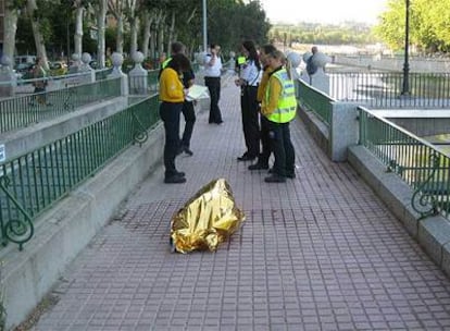 Miembros de la policía local junto al cadaver cubierto.