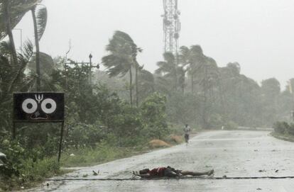 Un agricultor yace en el suelo tras intentar cruzar la carretera por los vientos raqueados, a las afueras de Puri (India), este viernes.