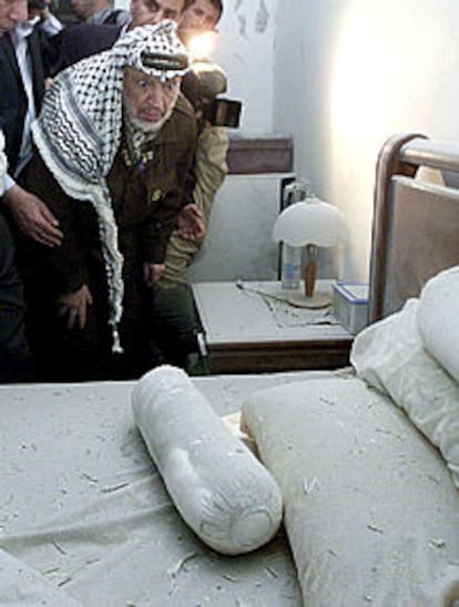 Arafat observa los daños producidos en su dormitorio por el ataque israelí.