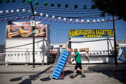 Un operario transporta varias cajas durante los preparativos para la feria de agosto en el Real de la Feria de Málaga.