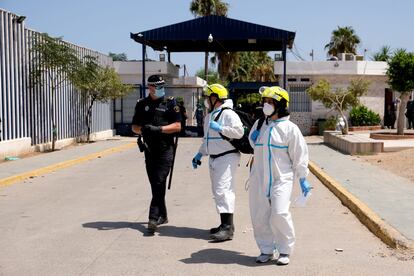 Dos sanitarios hablan con un policía en la puerta del Centro Temporal de Inmigrantes de Melilla.