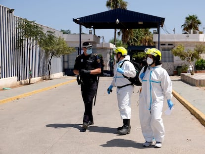 Dos sanitarios hablan con un policía en la puerta del Centro Temporal de Inmigrantes de Melilla.