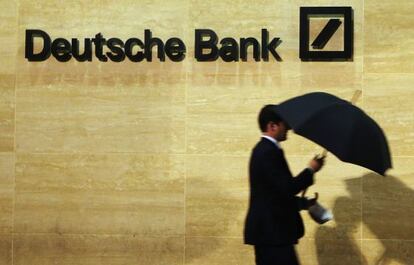 Un hombre pasa con su paraguas junto a una oficina de Deutsche Bank, en Londres.