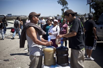 Los deportados hacen fila para recibir una torta (bocadillo) y un vaso de agua