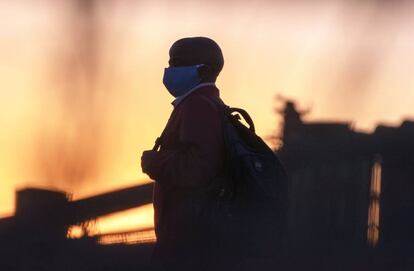 Un hombre con mascarilla para frenar el coronavirus regresa a casa desde el trabajo en Germiston, cerca de Johanesburgo, Sudáfrica.