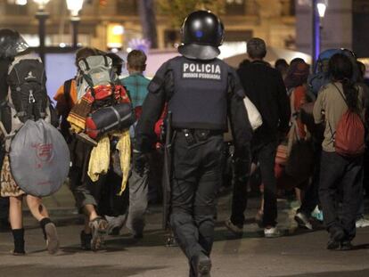 Varios acampados abandonan la plaza de Catalunya bajo la mirada de un 'mosso'.