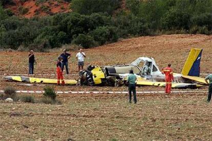 Guardias civiles, bomberos y técnicos, ayer, contemplan el avión de extinción que se estrelló tras despegar de la base de El Rebollar.