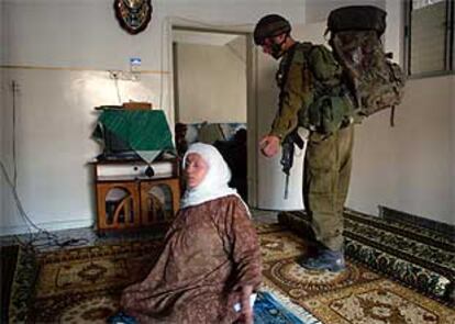 Una mujer palestina se sienta en el suelo de su casa mientras un soldado israelí registra su vivienda en Tulkarem.