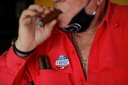 Un hombre fuma un habano mientras porta una pegatina que dice "¡yo voté!", esta semana en Miami.