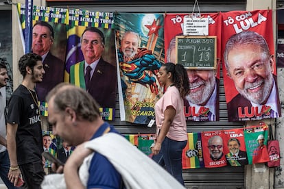 Varias personas caminan frente a un puesto callejero de toallas con imágenes del actual presidente de Brasil y candidato a la reelección, Jair Bolsonaro, y su contendiente, el expresidente brasileño Luiz Inácio Lula da Silva.