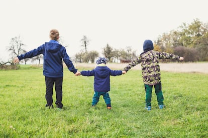 Tres niños se cogen la mano en el campo.