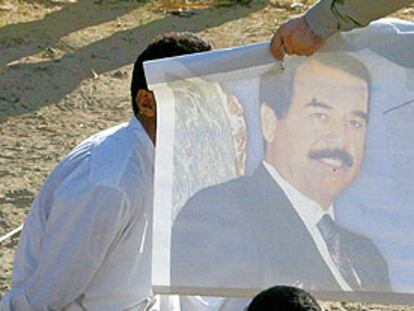 Soldados estadounidenses muestran un cartel de Sadam Husein a un detenido iraquí en Tikrit (norte).