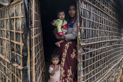 Ransia posa com seus dois filhos na porta de sua casa no campo de refugiados.