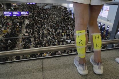 Una manifestante con un cartel de 'Free Hong Kong' en sus piernas se asoma ante los miles de manifestantes que han bloqueado el aeropuerto de Hong Kong, el 11 de agosto de 2019.