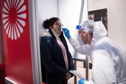 Un sanitario somete a un test de coronavirus a una pasajera, este jueves, en el aeropuerto Berlín-Brandenburg.