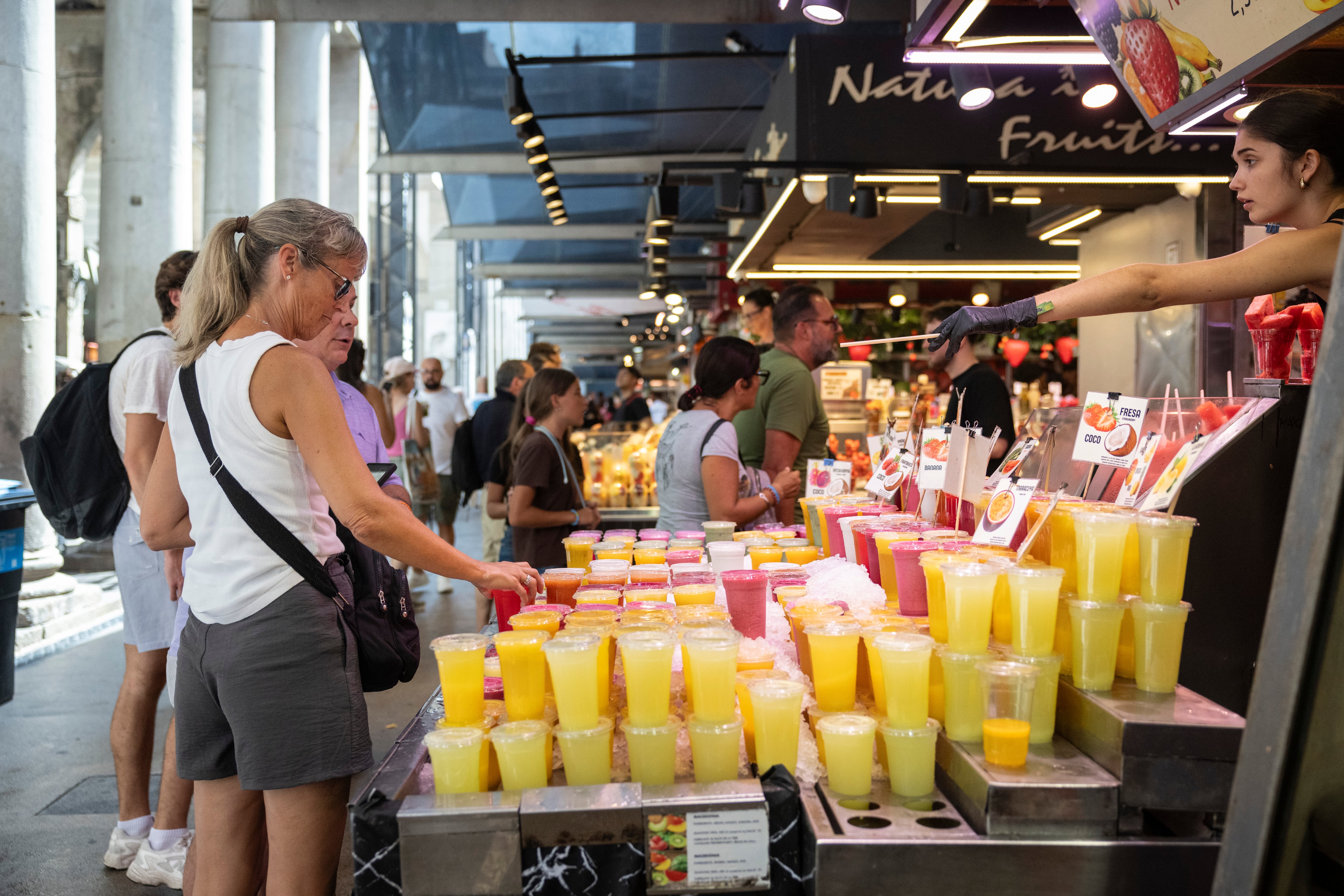 Turistas comprando de zumos de fruta preparados en una parada del mercado de La Boqueria de Barcelona, este jueves.