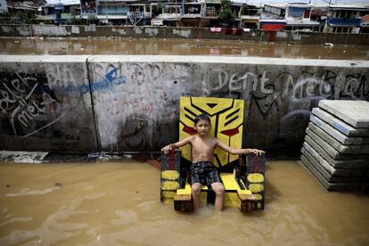 Un niño permanece sentado sobre un sillón en una calle inundada de Yakarta.