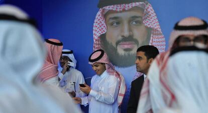 Un grupo de saudíes habla junto a un póster del príncipe heredero Mohammed bin Salman durante el Foro Misk, celebrado esta semana en Riad.