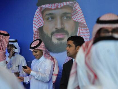 Un grupo de saud&iacute;es habla junto a un p&oacute;ster del pr&iacute;ncipe heredero Mohammed bin Salman durante el Foro Misk, celebrado esta semana en Riad.