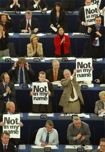 Diputados del Europarlamento aplauden el resultado de la votación mientras otros muestran su rechazo con pancartas que rezan "no en mi nombre".