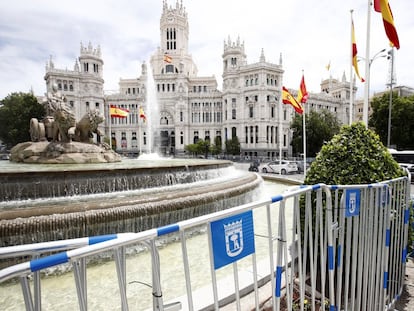 La fuente de la Cibeles, en Madrid, rodeada de vallas y banderas de España.