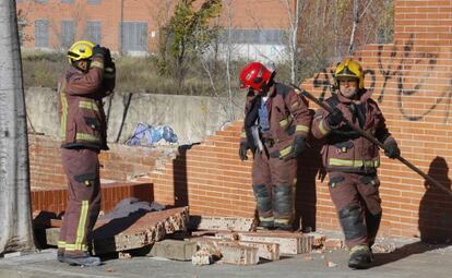 Un grupo de bomberos desescombra el muro caído en Terrassa.