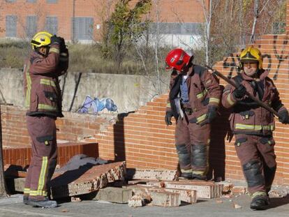 Un grupo de bomberos desescombra el muro caído en Terrassa.