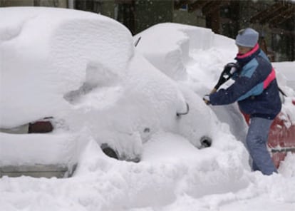 Un joven intenta descubrir uno de los coches que ha amenecido hoy totalmente cubierto por la nieve en las calles de Benasque, una de las poblaciones más afectadas por el temporal que afecta a Aragón.