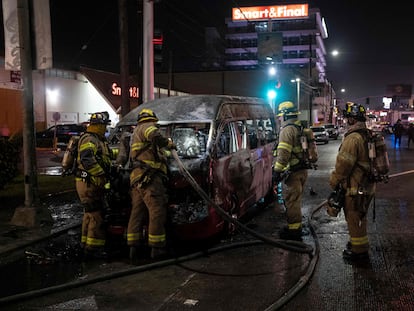 Bomberos trabajan alrededor de un vehículo de transporte público que fue incendiado, la noche del viernes, en Tijuana.