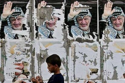 Un chico palestino pasa frente a varios carteles de Yasir Arafat en una calle de Gaza.