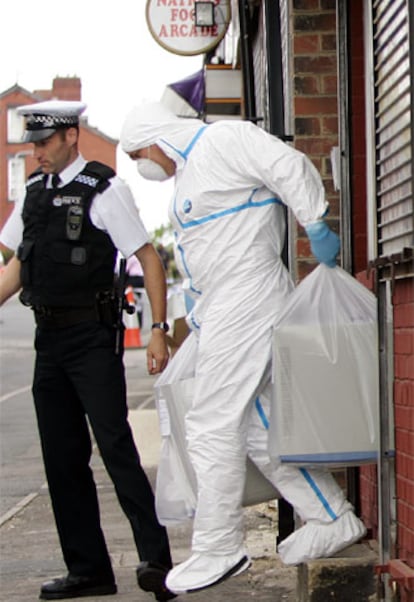 Un policía forense saca ordenadores de una propiedad en el barrio de Beeston, en Leeds.