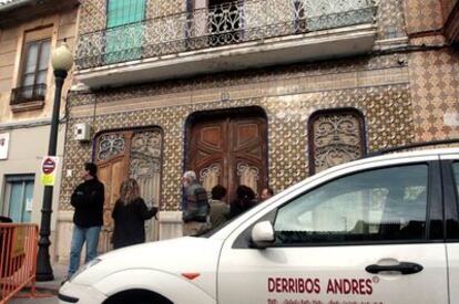 Vecinos a la puerta del número 131 de la calle de la Reina en El Cabanyal, ayer, después de la intervención en el interior de una empresa de derribos.